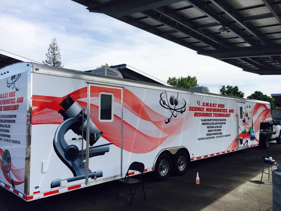 Large S.M.A.R.T. Kids science education trailer wrapped in red waves with microscope graphics
